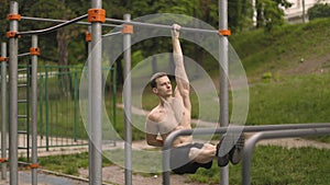 Young caucasian athlete with muscular torso doing corner on crossbar