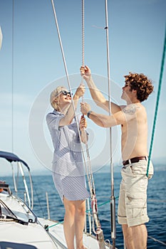 Young caucasian attractive couple navigating a yacht in caribbean sea