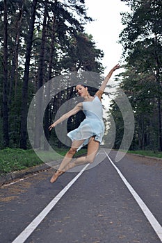 Delgado joven caucásico bailarín en la luz azul falda posando en saltando bailar durante en el verano Bosque 