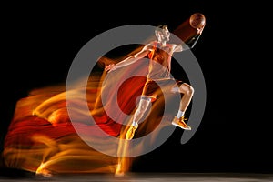 Young caucasian basketball player against dark background in mixed light