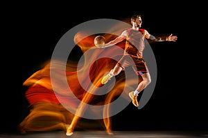 Young caucasian basketball player against dark background in mixed light