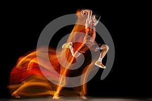 Young caucasian basketball player against dark background in mixed light