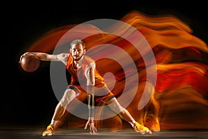 Young caucasian basketball player against dark background in mixed light