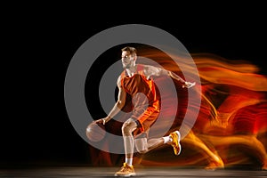 Young caucasian basketball player against dark background in mixed light