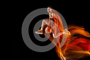 Young caucasian basketball player against dark background in mixed light