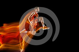 Young caucasian basketball player against dark background in mixed light