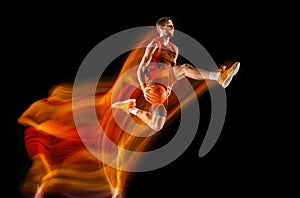 Young caucasian basketball player against dark background in mixed light
