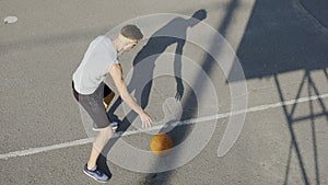 Young Caucasian basketball player dribbling a ball at stadium, sport and hobby