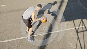 Young Caucasian basketball player dribbling a ball at stadium, sport and hobby