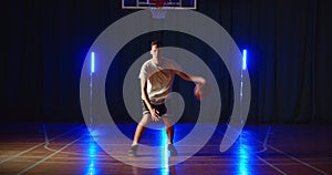 Young caucasian basketball player dribbling training ball tricks neon blue light background