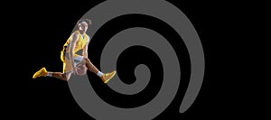 Young Caucasian basketball player training isolated on black background.