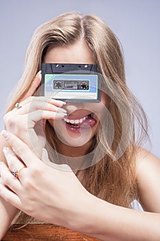 Young Caucasian Blond Woman Holding Audio Cassette In Front