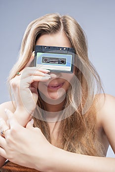 Young Caucasian Blond Woman Holding Audio Cassette In Front