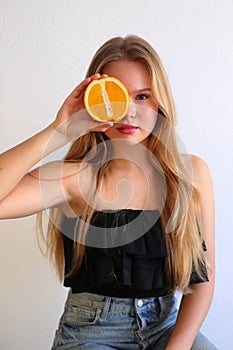 Young caucasian blonde girl with orange citrus fruit, healthy concept