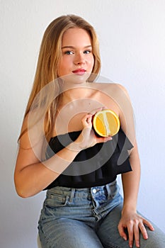 Young caucasian blonde girl with orange citrus fruit, healthy concept