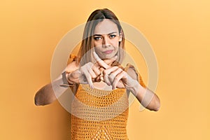 Young caucasian blonde woman wearing casual yellow t shirt rejection expression crossing fingers doing negative sign