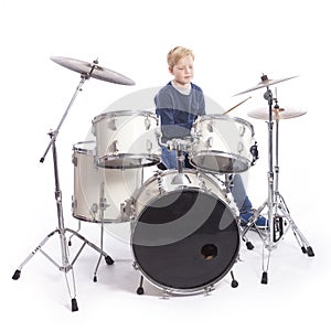 Young caucasian boy at drum kit in studio plays music