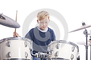 Young caucasian boy at drum kit in studio plays music