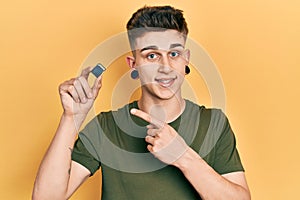 Young caucasian boy with ears dilation holding sdxc card smiling happy pointing with hand and finger