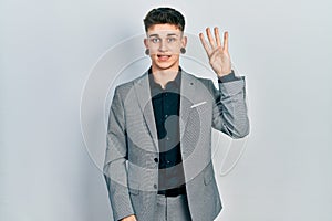 Young caucasian boy with ears dilation wearing business jacket showing and pointing up with fingers number four while smiling