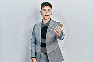 Young caucasian boy with ears dilation wearing business jacket smiling friendly offering handshake as greeting and welcoming