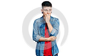 Young caucasian boy with ears dilation wearing casual denim jacket looking stressed and nervous with hands on mouth biting nails