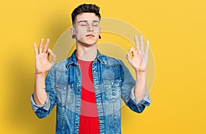 Young caucasian boy with ears dilation wearing casual denim jacket relax and smiling with eyes closed doing meditation gesture