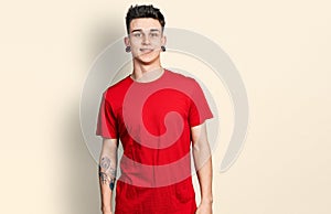 Young caucasian boy with ears dilation wearing casual red t shirt with a happy and cool smile on face