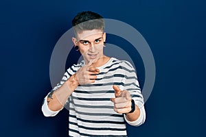 Young caucasian boy with ears dilation wearing casual striped shirt pointing fingers to camera with happy and funny face