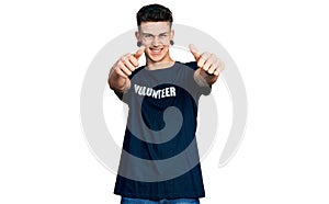 Young caucasian boy with ears dilation wearing volunteer t shirt approving doing positive gesture with hand, thumbs up smiling and