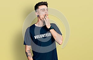 Young caucasian boy with ears dilation wearing volunteer t shirt bored yawning tired covering mouth with hand
