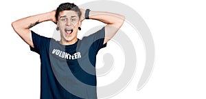 Young caucasian boy with ears dilation wearing volunteer t shirt crazy and scared with hands on head, afraid and surprised of