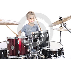 young caucasian boy plays drums in studio against white background