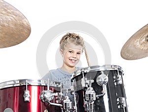 young caucasian boy plays drums in studio against white background