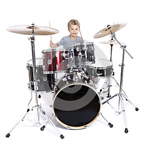 young caucasian boy plays drums in studio against white background