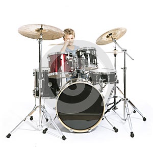 young caucasian boy plays drums in studio against white background