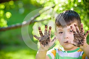 A young Caucasian boy showing off his dirty hands after playing