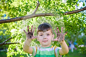 A young Caucasian boy showing off his dirty hands after playing in dirt and sand