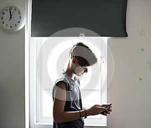 Young caucasian boy using mobile phone in bedroom