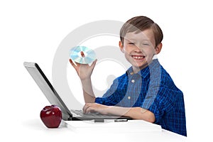 Young caucasian boy working on laptop with a CD