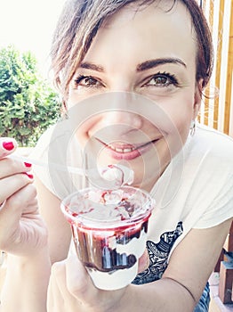 Young caucasian brunette eating creamy ice cream with strawberry