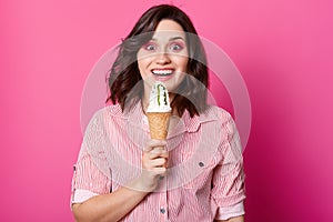 Young Caucasian brunette girl with wavy hair on pink background. Stylish young woman with ice cream isolated over pink studio