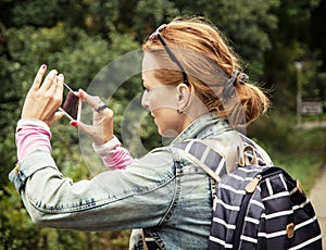 Young caucasian brunette woman takes photo in the park photo