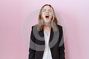 Young caucasian business woman wearing black jacket angry and mad screaming frustrated and furious, shouting with anger