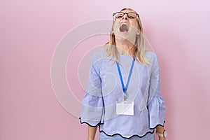 Young caucasian business woman wearing id card angry and mad screaming frustrated and furious, shouting with anger