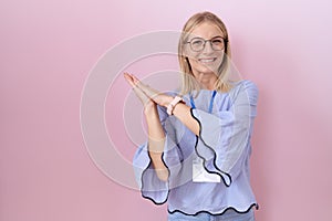 Young caucasian business woman wearing id card clapping and applauding happy and joyful, smiling proud hands together