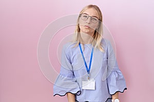 Young caucasian business woman wearing id card looking at the camera blowing a kiss on air being lovely and sexy