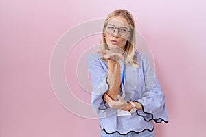 Young caucasian business woman wearing id card looking at the camera blowing a kiss with hand on air being lovely and sexy