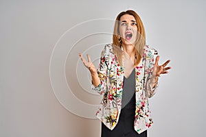 Young caucasian business woman wearing spring floral jacket suit over isolated background crazy and mad shouting and yelling with