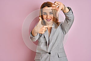 Young caucasian business woman wearing a suit over isolated pink background smiling making frame with hands and fingers with happy